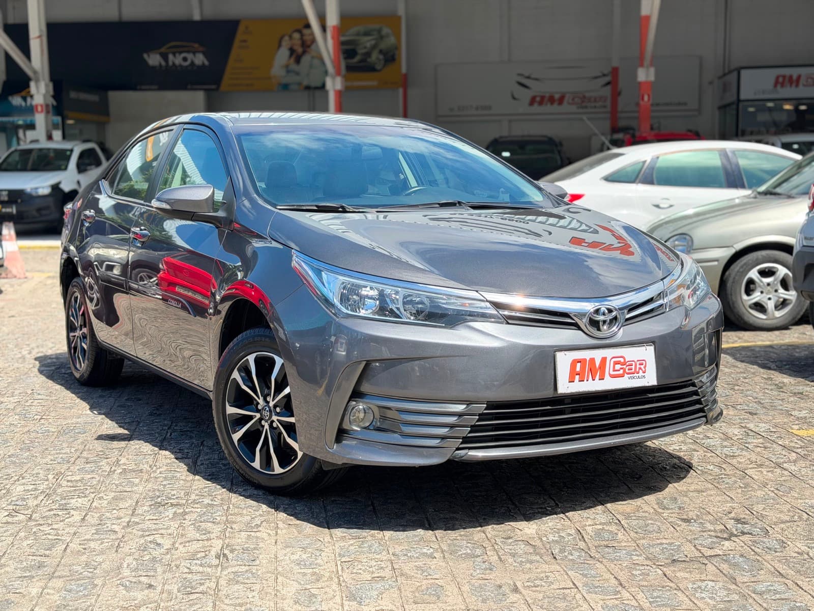 Toyota Corolla GLi cinza visto de três quartos dianteiro, no pátio da AMCar